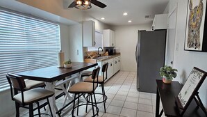 Una cocina moderna con una isla central, ventilador de techo y refrigerador.