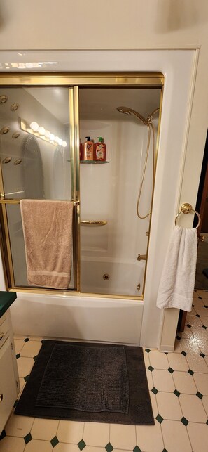 A bathroom with a glass-enclosed shower, a bathtub, and a vanity with a towel rack.
