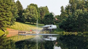 Ein Anwesen am Seeufer mit Haus, Springbrunnen und Steg.