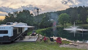 A lakeside RV campsite with a dock, a red barn, and a fountain. - Waterfront RV Escape in Amish Country (Glenmont)