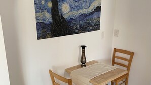 Un coin repas avec une table et des chaises, un tableau accroché au mur et un vase posé sur la table.