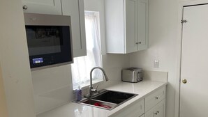 Une cuisine moderne avec des meubles blancs, un four à micro-ondes encastré, un évier et un grille-pain.