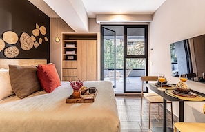 A modern bedroom with a large bed, a dining area with breakfast setup, and a view of the outdoors through a sliding door. - Kukun Homero Polanco (Mexico City)