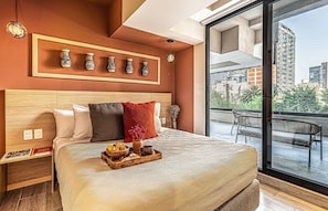 A modern hotel room with a large bed, a wooden headboard, a tray with breakfast items, and a balcony with a view of the city. - Kukun Homero Polanco (Mexico City)