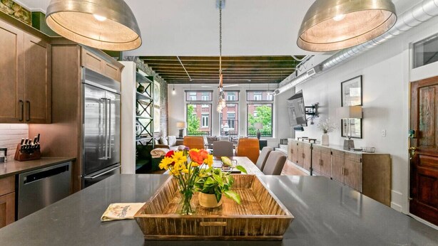 A modern kitchen with stainless steel appliances, a central island with a woven tray, and pendant lighting.