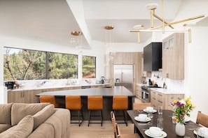 A modern kitchen with a large island, wooden cabinets, and a dining area with a table set for four.