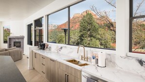 Una cucina moderna con ampie finestre, un camino e vista sulle formazioni rocciose rosse.