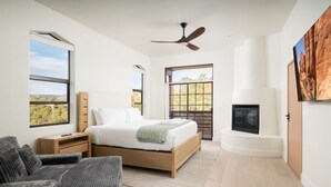 Una camera da letto con un letto, comodini, un divano, un camino e ampie finestre.