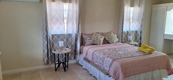 A bedroom with a bed, curtains, a bedside table, and a lamp.
