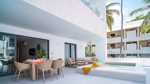 Uma área externa moderna com mesa de jantar, cadeiras, sofá e piscina.