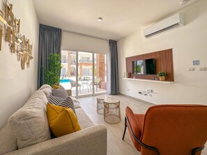 A modern living room with a sofa, a coffee table, and a TV mounted on the wall.