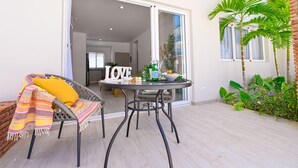 A balcony with a wicker chair, a small round table, and a 'LOVE' sign.