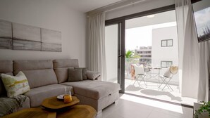 A modern living room with a sofa, coffee table, and a balcony with outdoor furniture.