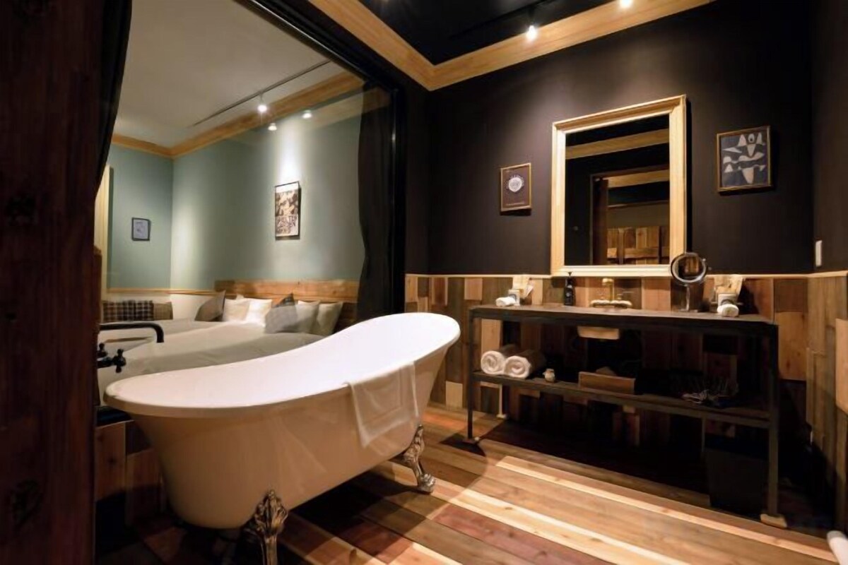 A modern bathroom with a freestanding bathtub, a vanity with a mirror, and a wooden floor.