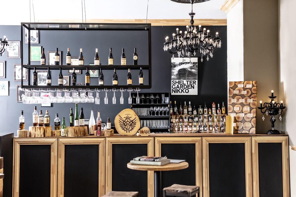 Zona de bar con estantes llenos de botellas, vasos y una barra de madera.