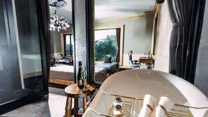 Camera d'hotel moderna con una grande vasca da bagno, un tavolino in legno con una bottiglia e un bicchiere, e vista all'esterno.