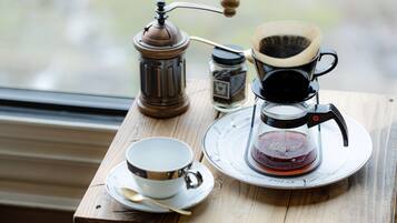 Une machine à café, une tasse et un bocal sur une table en bois près d’une fenêtre.