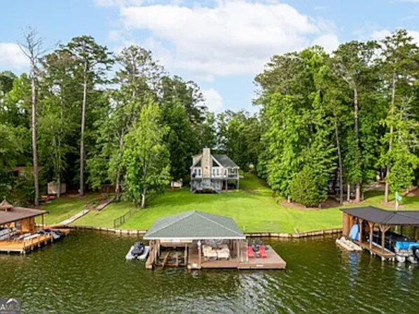 Une propriété au bord du lac comprenant une maison, un quai et un bateau.