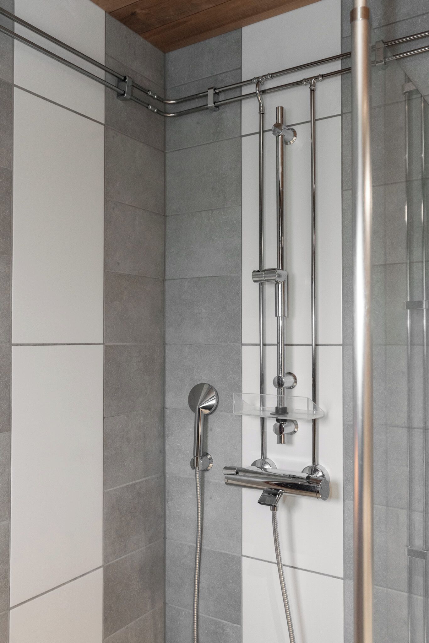 A shower with a glass enclosure, chrome fixtures, and a tiled wall.