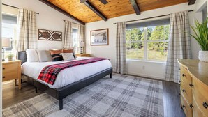 A bedroom with a bed, a ceiling fan, a window with curtains, a nightstand, and a dresser.