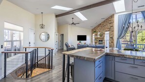 A spacious kitchen with a large island, a dining area with a leather couch, and a stone accent wall.