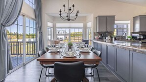 A spacious dining area with a large wooden table, black chairs, and a chandelier.