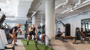 A gym with exercise equipment, a treadmill, and a green mat area.