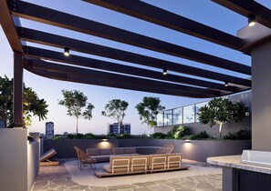 An outdoor patio with a pergola, seating area, and a view of the cityscape.