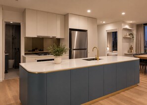 A modern kitchen with a central island, stainless steel appliances, and a potted plant.