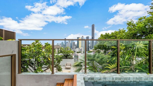 A rooftop terrace with a pool, city skyline view, and lush greenery. - Spacious & stylish apartment in James Street Precinct with pool, gym and rooftop (Fortitude Valley)