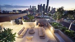 A rooftop terrace with outdoor seating, a fire pit, and a city skyline view in the background. - Spacious & stylish apartment in James Street Precinct with pool, gym and rooftop (Fortitude Valley)