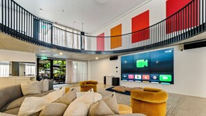 A spacious lobby with a seating area, a staircase, and a large digital display. - Spacious & stylish apartment in James Street Precinct with pool, gym and rooftop (Fortitude Valley)