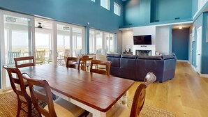 Un amplio salón con una mesa de comedor de madera, un sofá gris y un televisor.