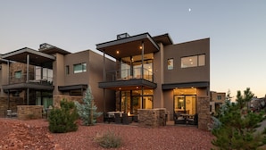 A modern multi-story house with a stone facade, outdoor seating area, and a visible staircase. - Luxury Townhome - Exclusive guest access to a members-only golf club and resort amenities. (Sedona)