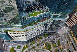 A modern high-rise building with a unique angular design, featuring multiple levels and a rooftop garden.