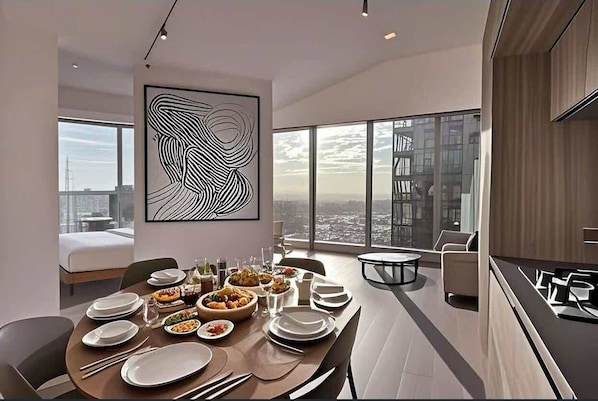 A modern dining area with a large table set for a meal, a city view through large windows, and a contemporary art piece on the wall.