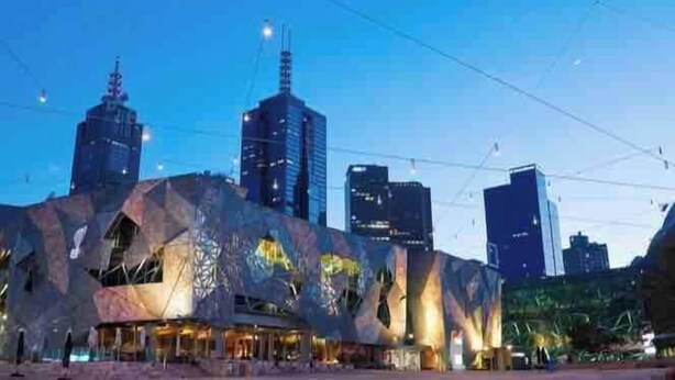 A modern building with a unique geometric facade, surrounded by high-rise buildings. - Garden-View Apartment: Pool, Spa, Gym Access (Caulfield North)