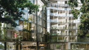 Un edificio moderno de varios pisos con fachadas de vidrio, zonas de estar al aire libre y un patio central.