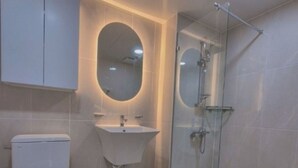 Une salle de bain moderne équipée de toilettes, d’un lavabo et d’une douche à parois de verre.