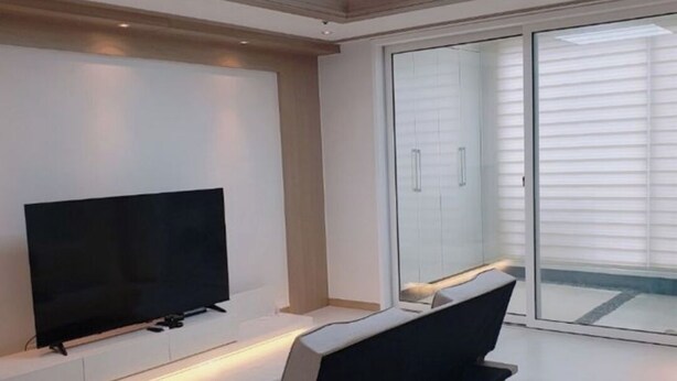 Un salon moderne avec un téléviseur à écran plat, un canapé et une table à manger.