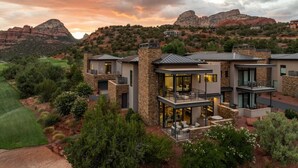 A modern multi-story house with a stone facade, large windows, and a spacious outdoor patio area. - Luxury Townhome - Exclusive guest access to a members-only golf club and resort amenities including pool. (Sedona)