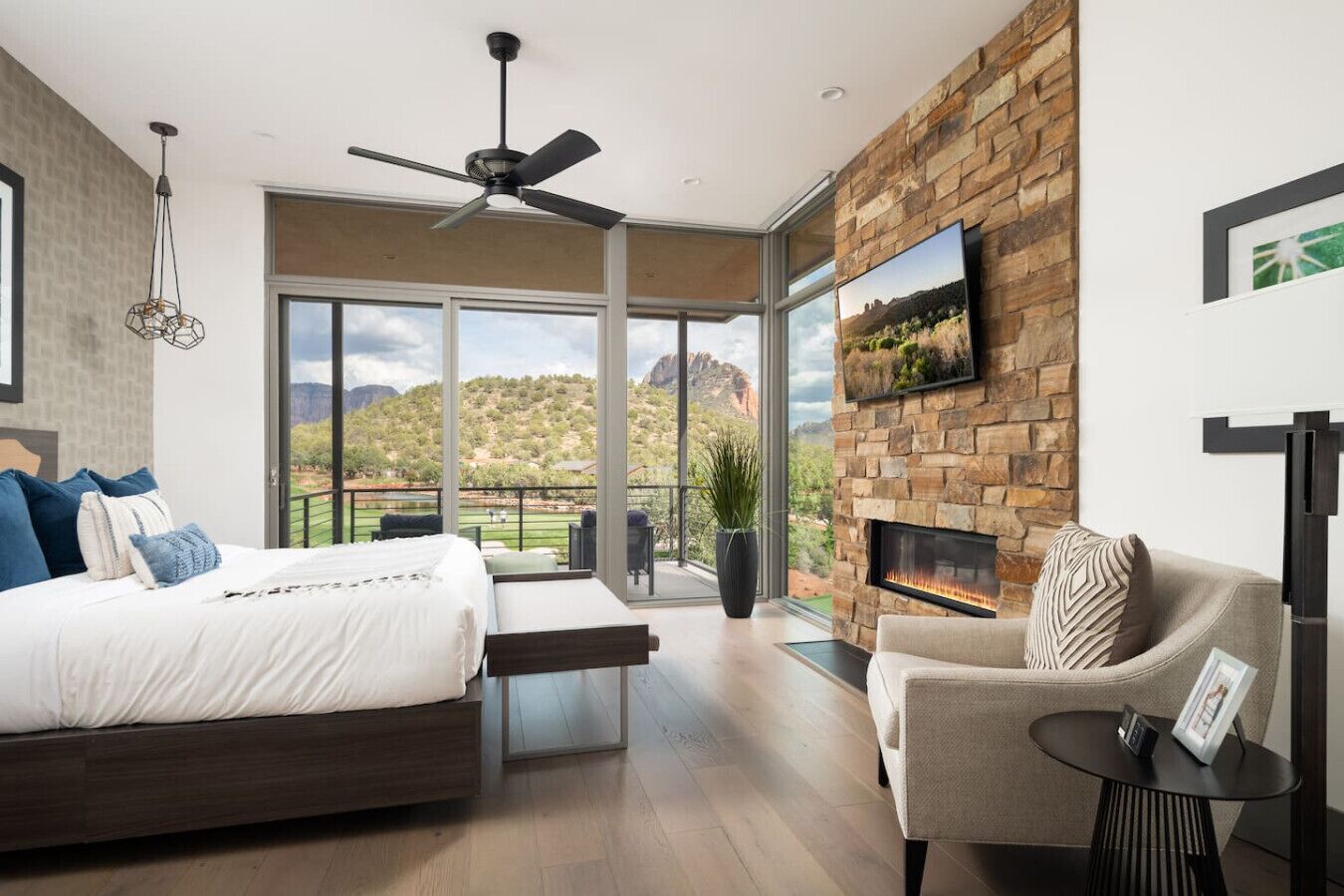 Une chambre moderne dotée d’un grand lit, d’un canapé, d’une cheminée et d’un balcon offrant une vue sur les montagnes.