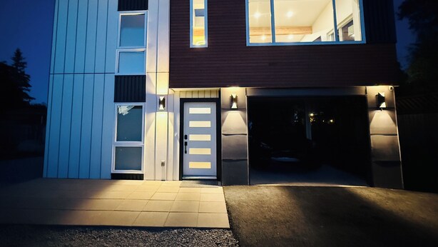 Une maison moderne à deux étages, dotée d’un garage, d’une porte d’entrée et d’une allée.