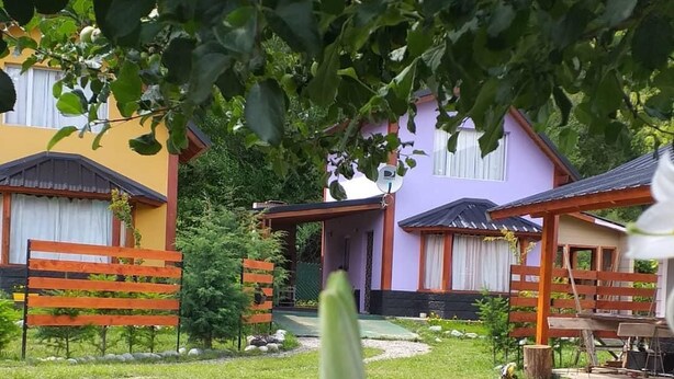 Ein Gartenbereich mit Holzbänken, einem Weg und einem kleinen Tisch mit Stühlen.