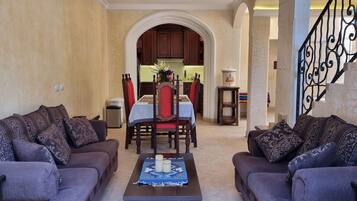 A living room with two sofas, a coffee table, and a dining area with a table and chairs.