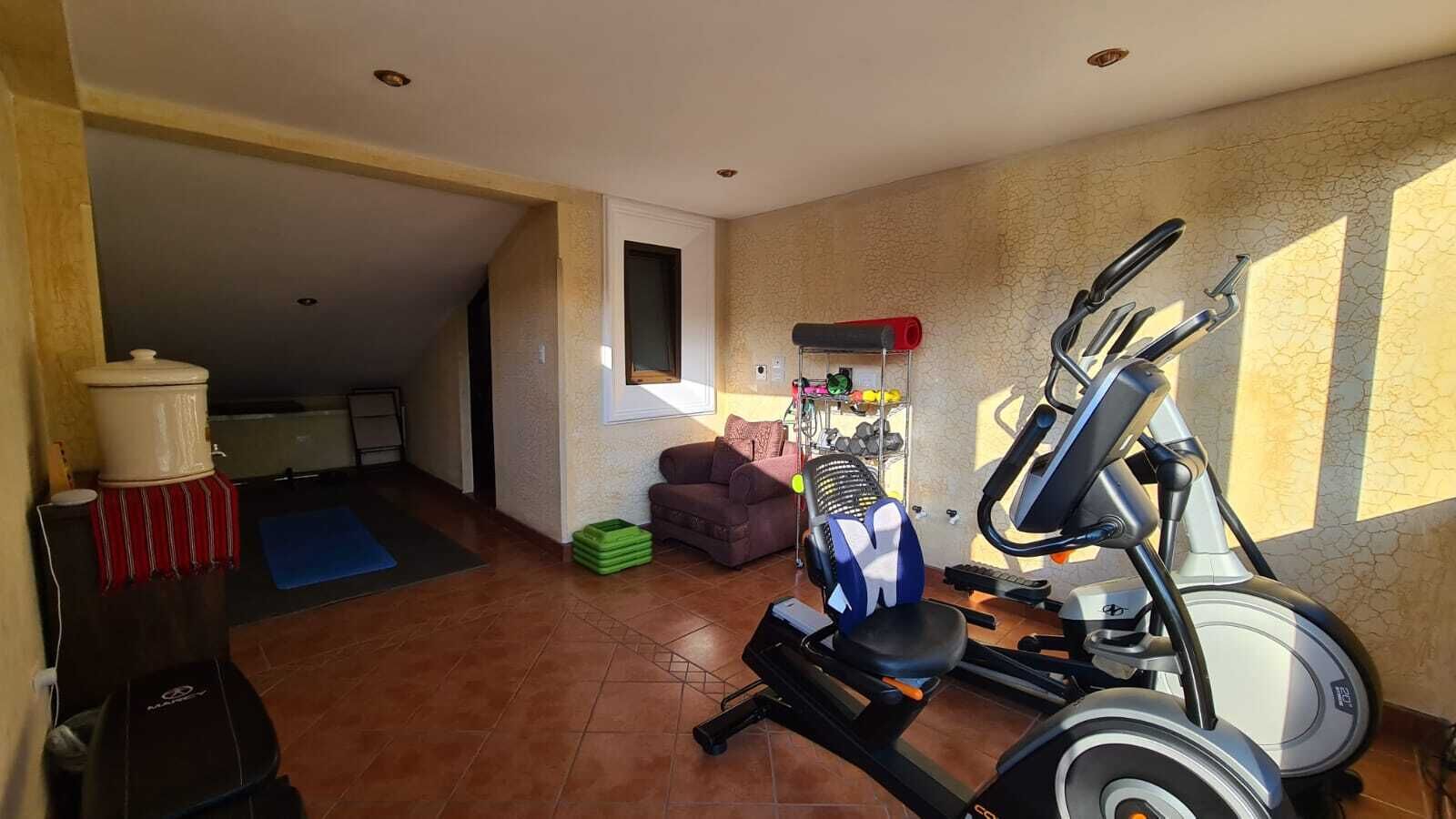 A home gym with exercise equipment, a yoga mat, and a small couch.