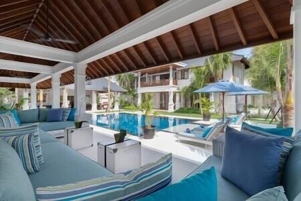 A poolside area with lounge chairs and a covered seating area.
