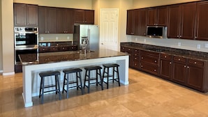 A modern kitchen with dark wood cabinets, stainless steel appliances, and a granite countertop. - Spacious 4-bedroom house in cool Phoenix with AC (Phoenix)