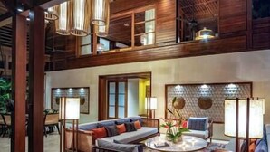 A spacious, multi-level living area with a high ceiling, wooden beams, and a mix of seating arrangements including a sofa and chairs. - Villa Windu Sari by Elite Havens (Seminyak)