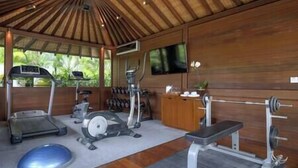 A gym with exercise equipment including treadmills, an elliptical, a stationary bike, and a bench press. - Villa Windu Sari by Elite Havens (Seminyak)